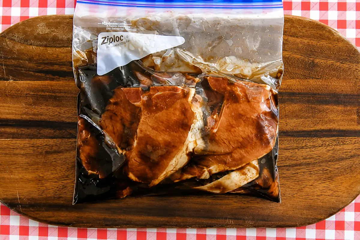 Bone-in pork chops coated with marmalade marinade in a Ziploc bag.