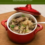 Mushroom rice with sliced mushrooms and chopped parsley served in a red dish.