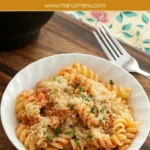 Bowl of tuna tomato pasta topped with garlic breadcrumbs and parsley.