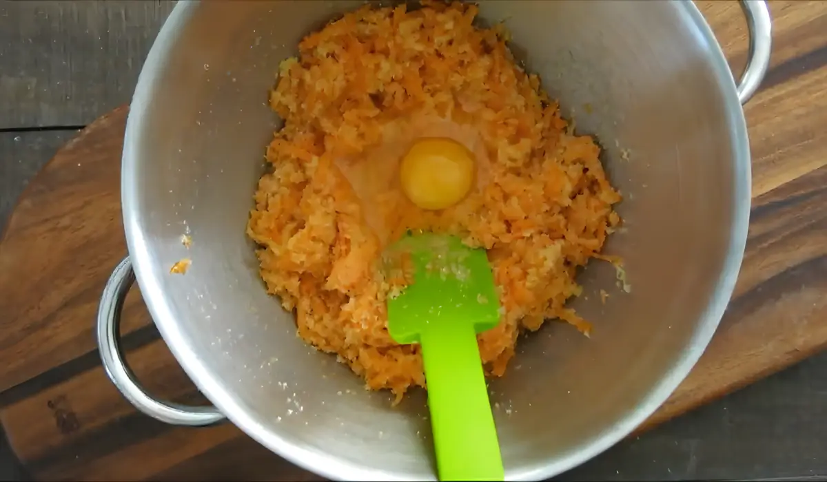 An egg added to the carrot and almond mixture before combining.