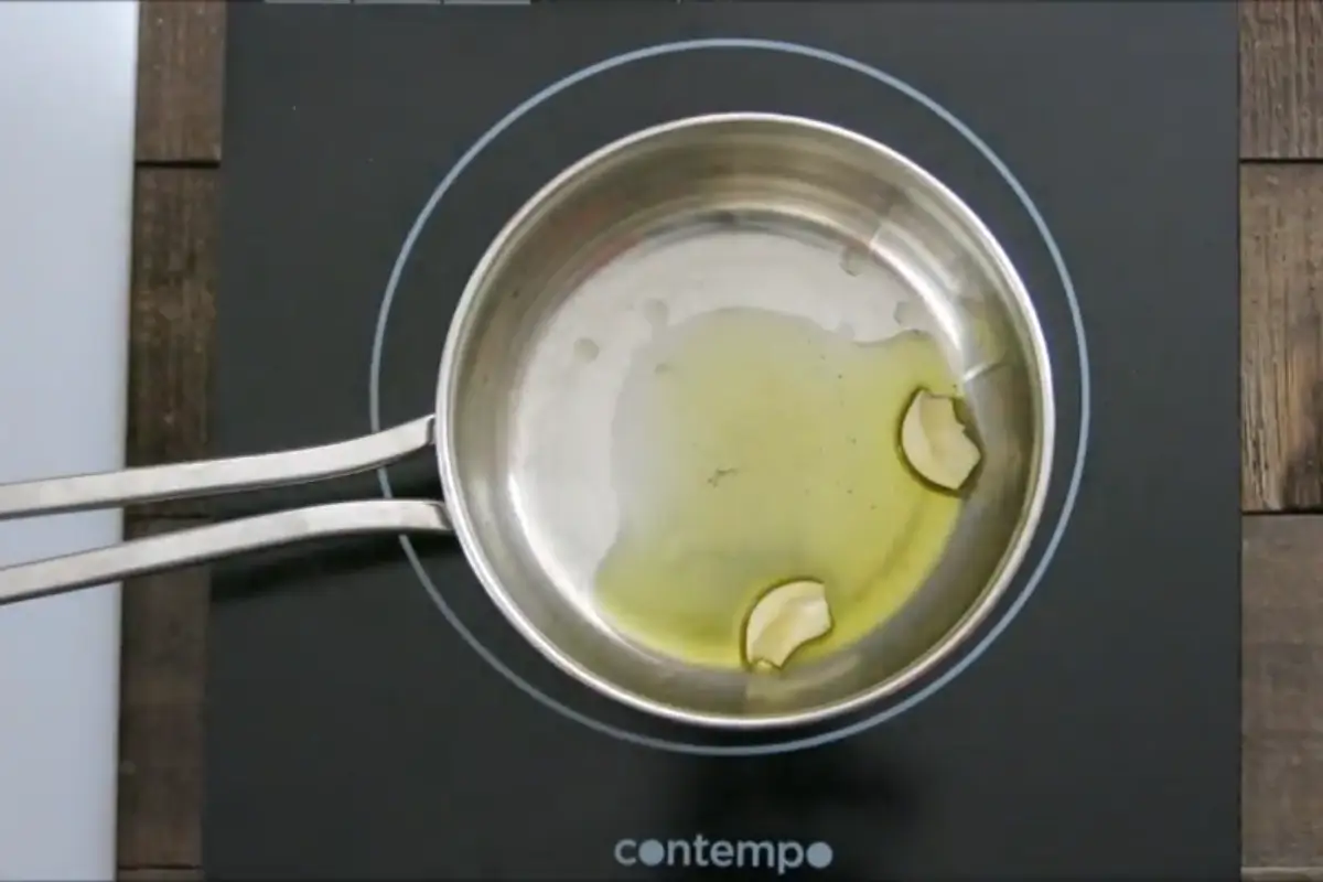Garlic sautéing in extra virgin olive oil in a small pot.