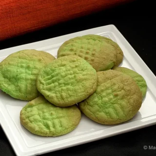 Green Buttercream Cookies with golden edges served on a white square plate.