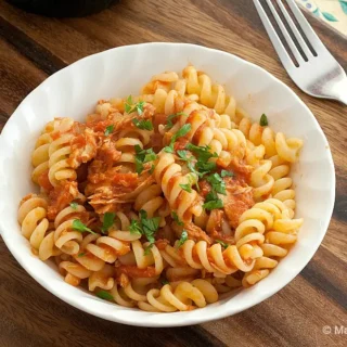Bowl of tuna tomato pasta topped with garlic breadcrumbs and parsley