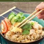 Bowl of Thai chicken fried rice garnished with cucumber, tomato, and coriander.
