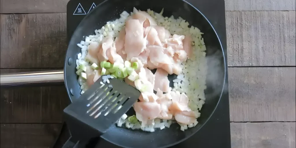 Chicken pieces and green onions added to the sautéed onion mixture.