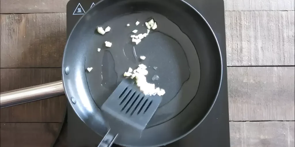 Chopped garlic sautéing in oil in a wok.