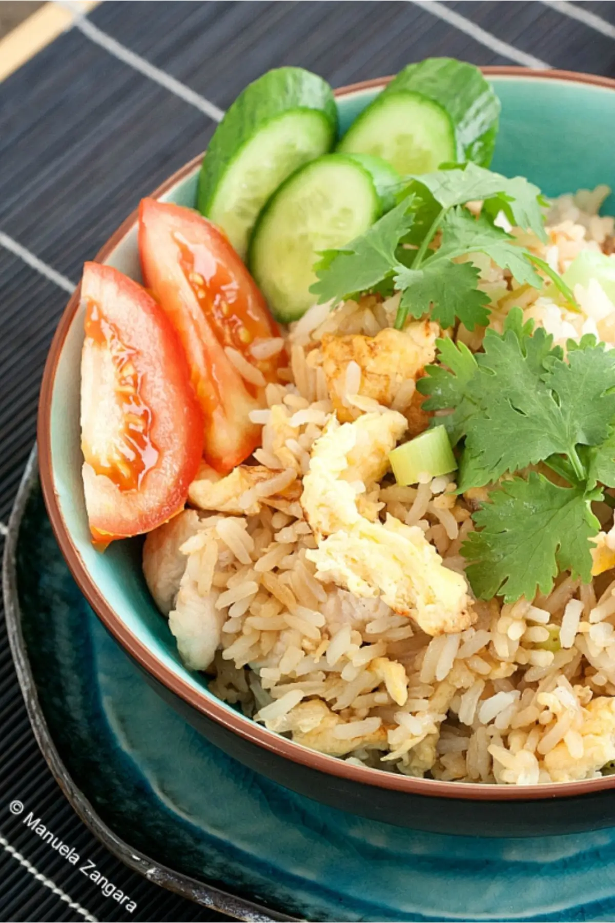 Thai chicken fried rice served in a bowl with fresh vegetables on the side.