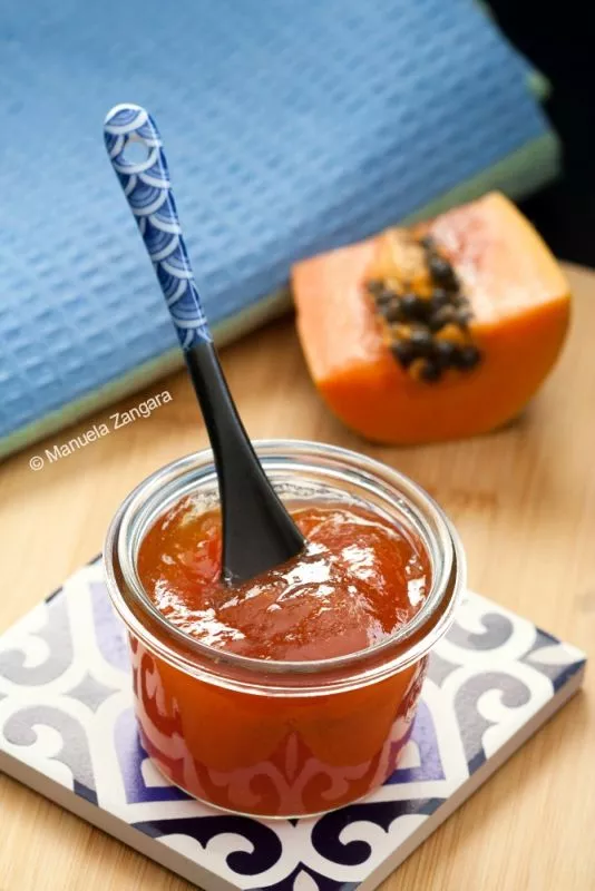 Papaya jam recipe shown in a jar with a blue patterned spoon and sliced papaya for a tropical finish.