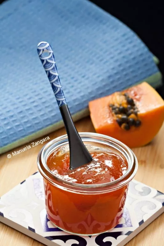 Close-up of thick tropical jam on a spoon showing the glossy texture of this easy papaya jam recipe.