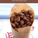 Almond pralines spilling from a paper cone onto the table.
