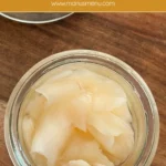 A small glass jar of pickled ginger placed on a wooden board.