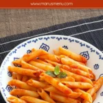 Bowl of penne coated in tomato sauce with a mint leaf on top.