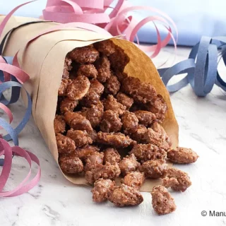 Almond pralines spilling from a paper cone onto the table.