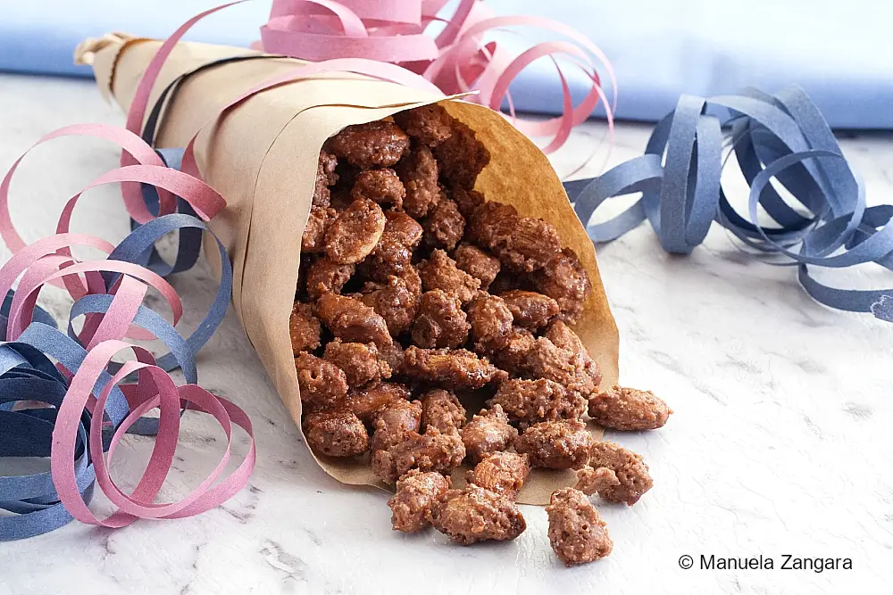 Almond pralines spilling from a paper cone onto the table.