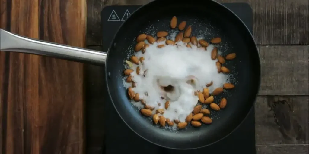 Almonds, sugar, and cocoa heating in a non-stick pan.