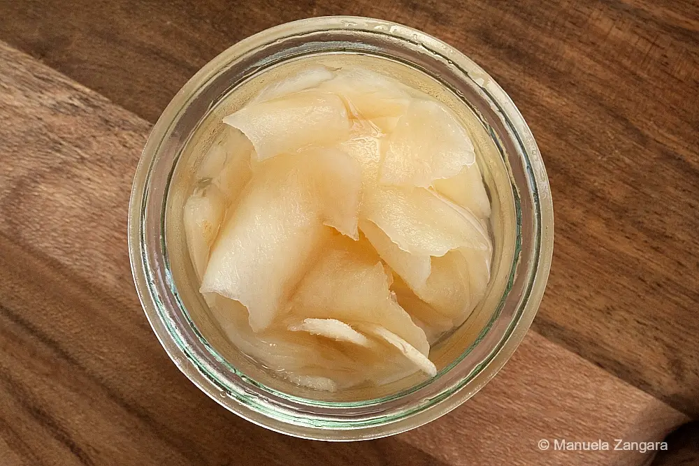 Close-up of homemade Japanese pickled ginger slices sitting in their brine.