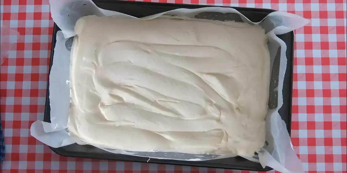 Smooth lemon cake batter spread evenly in a lined baking pan.