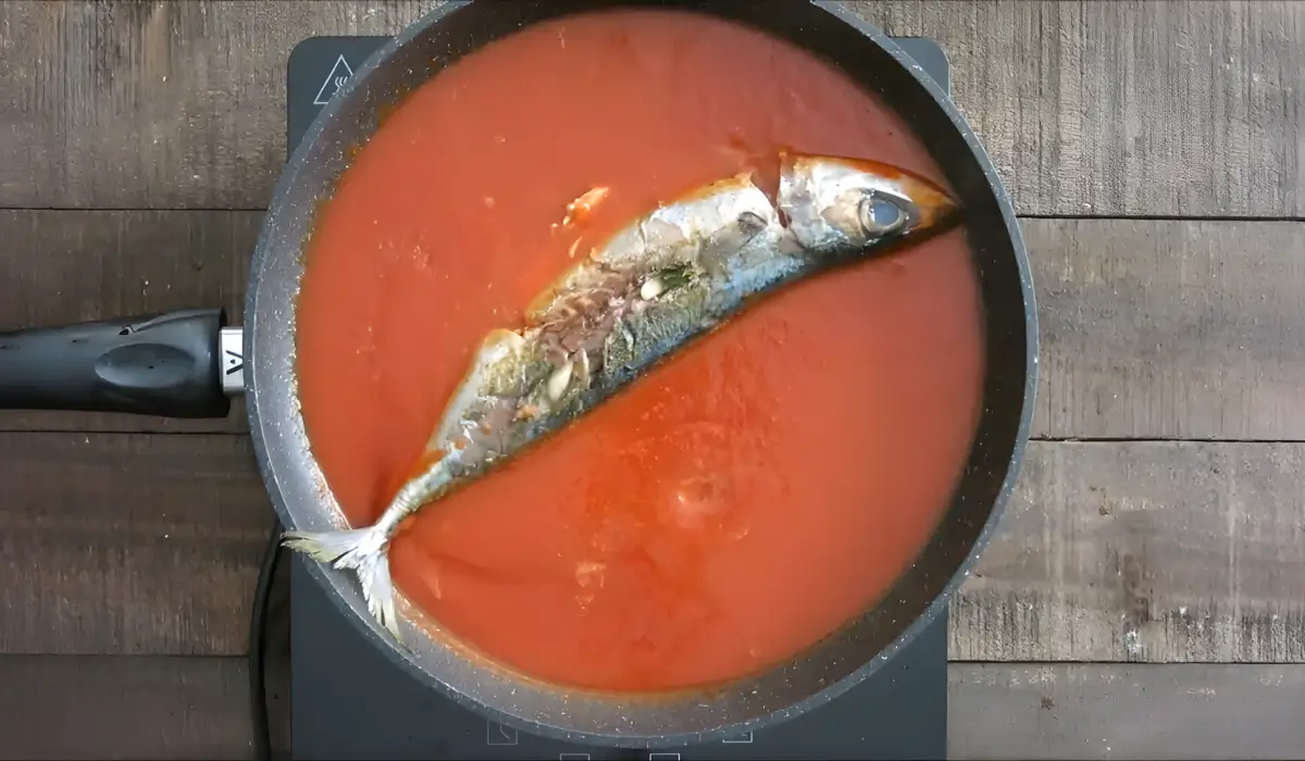 Whole mackerel simmering in a pan of tomato sauce.