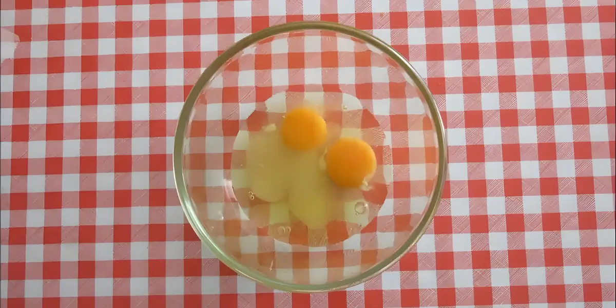 Eggs and lemon mixture in a glass bowl on a red checkered tablecloth.