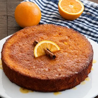 Orange polenta cake served with syrup and fresh oranges on the side.