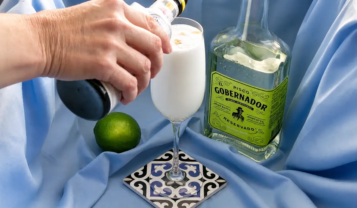 Adding Angostura bitters over the creamy foam of a freshly made cocktail.