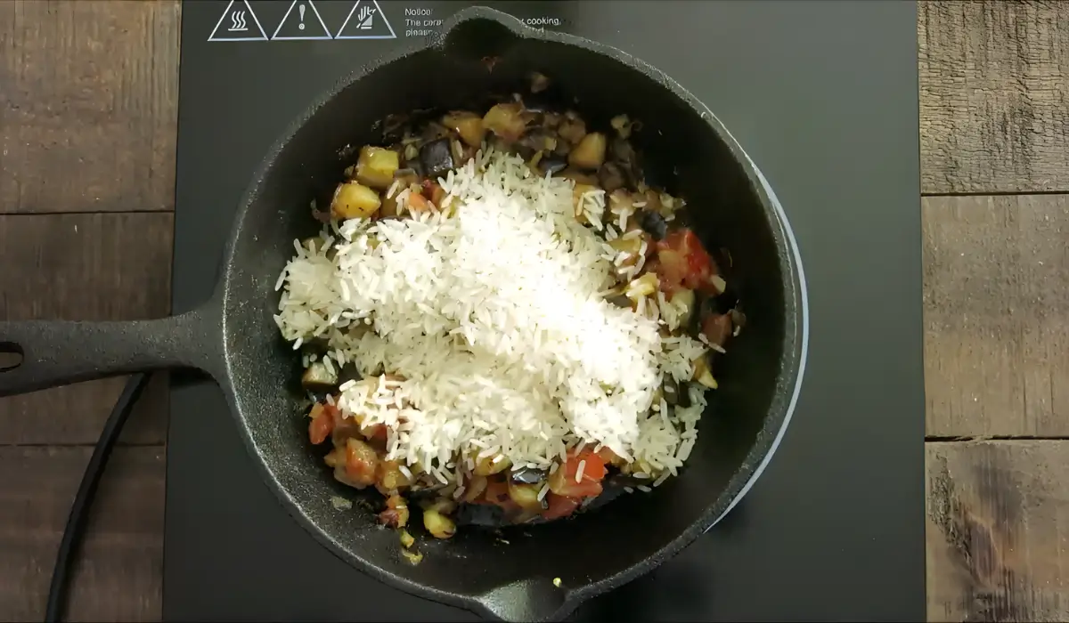 Uncooked rice added to the cooked eggplant and tomato mixture.