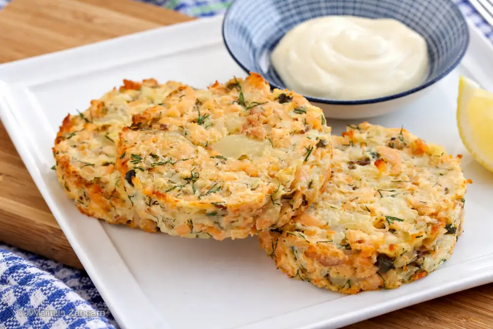 Golden baked salmon patties served with lemon and a side of sauce.