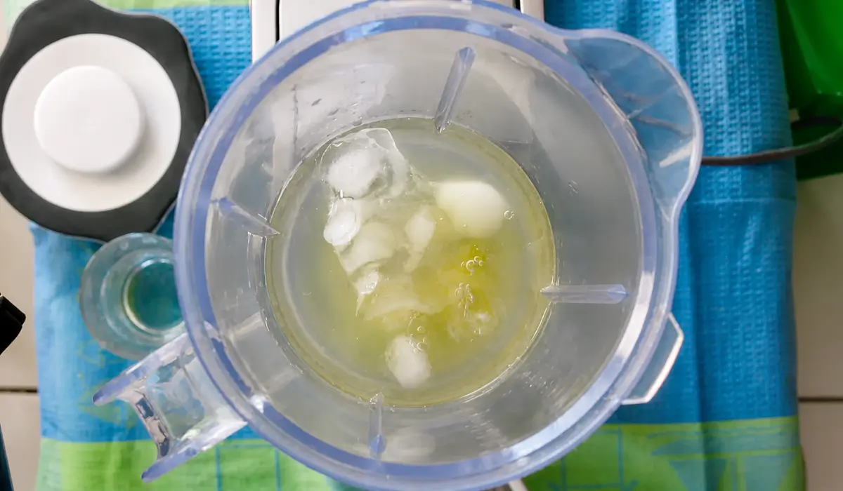 Pisco, lime juice, egg white, simple syrup, and ice inside a blender before mixing.