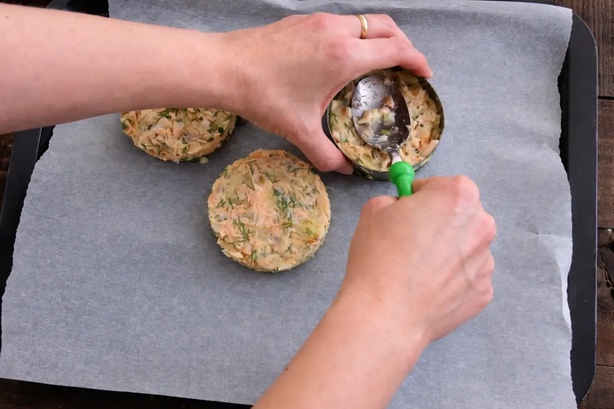 Salmon mixture shaped into patties and arranged on a lined baking tray.