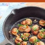 Golden scallops topped with fresh parsley and garlic butter inside a skillet.