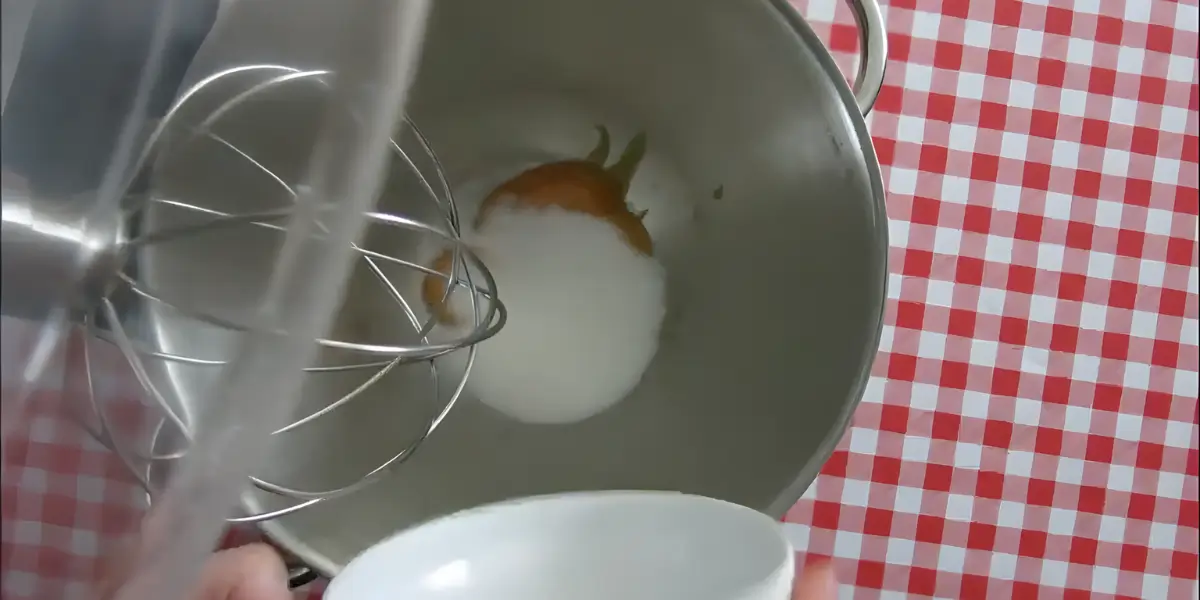 Egg yolks and sugar being beaten in a mixing bowl.