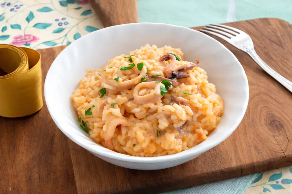 Creamy risotto served in a bowl with tender calamari pieces and fresh parsley on top.