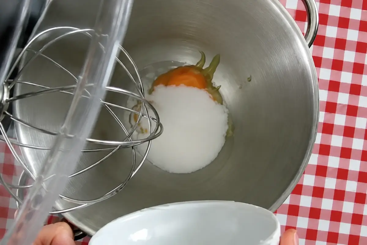 Egg yolks and sugar being prepared before whisking into a smooth mixture.