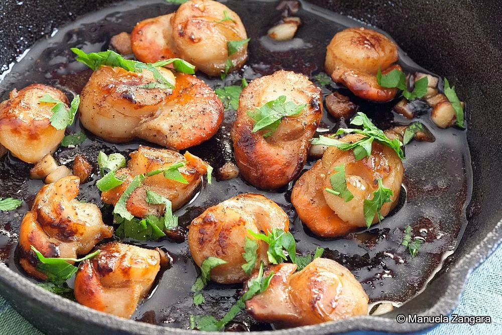 Scallops with garlic and parsley in a skillet.