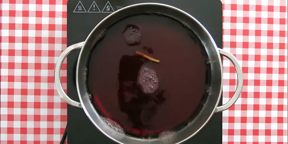 Malbec wine simmering with a cinnamon stick in a pot.