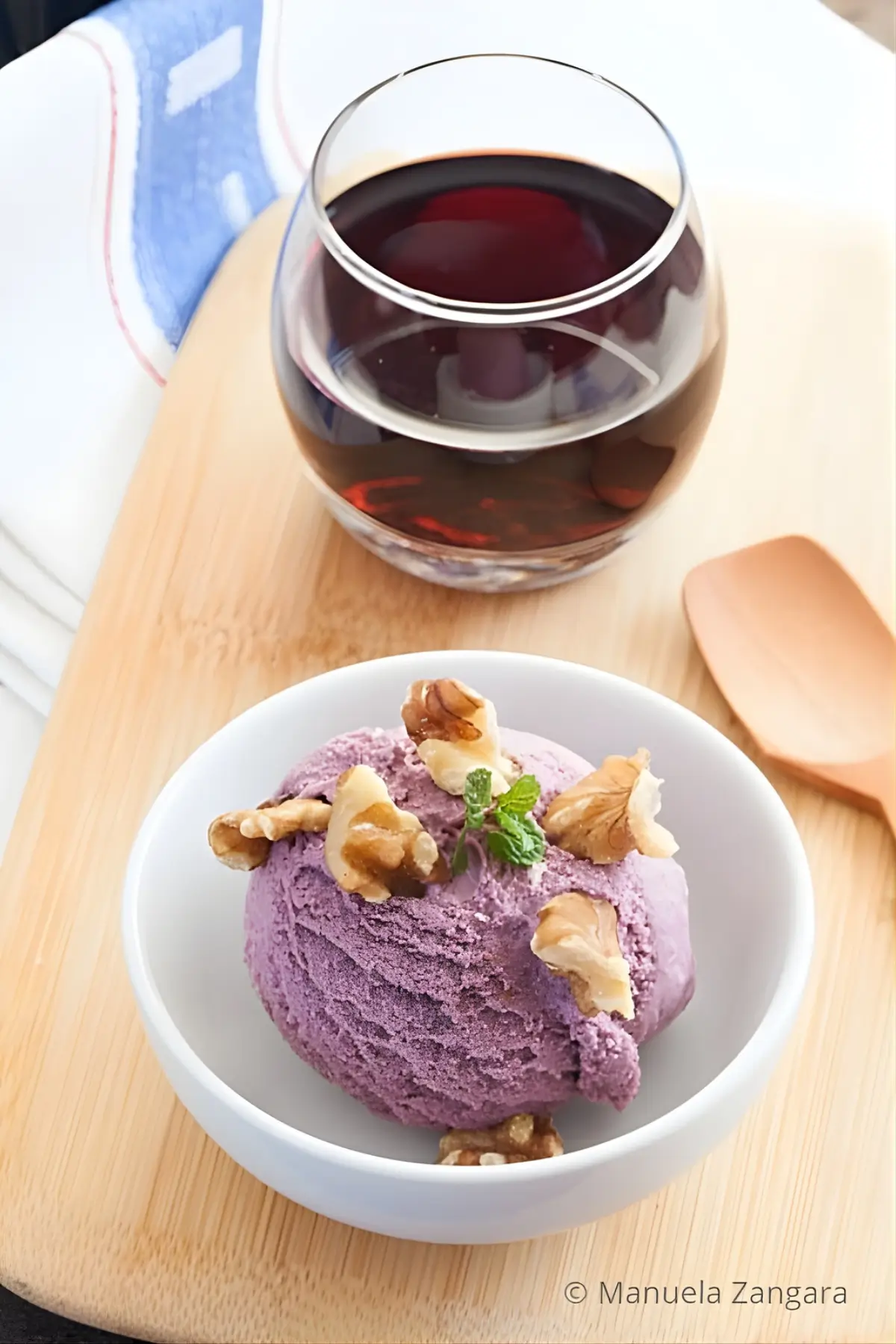 A scoop of Malbec ice cream topped with walnuts, served with a glass of red wine.