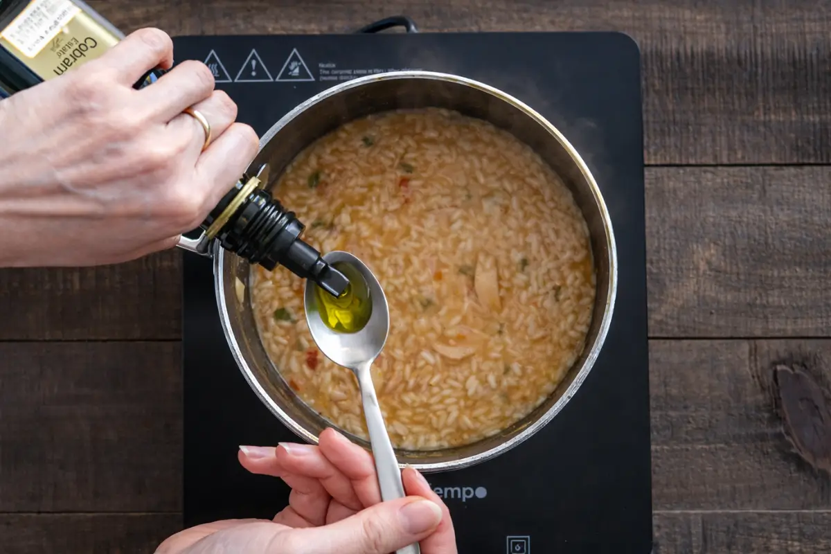 Adding garlic-infused oil to finish the risotto before serving.