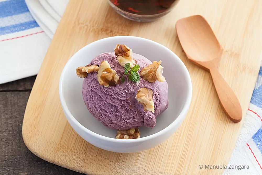 Close-up of Malbec ice cream with walnuts and mint in a white bowl.