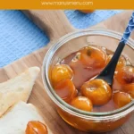 Kumquat jam in a jar with toast and fresh kumquats arranged on a wooden board.