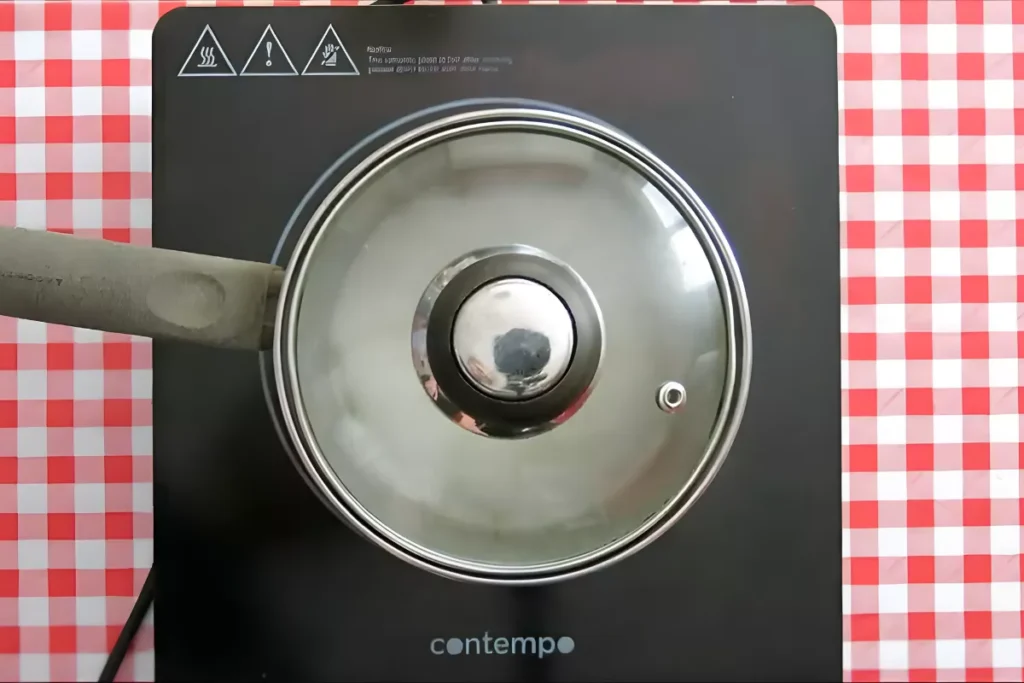 Pot covered with a lid while long grain rice cooks over low heat.