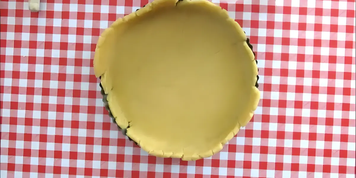 Rolled dough pressed into a tart tin and trimmed at the edges.