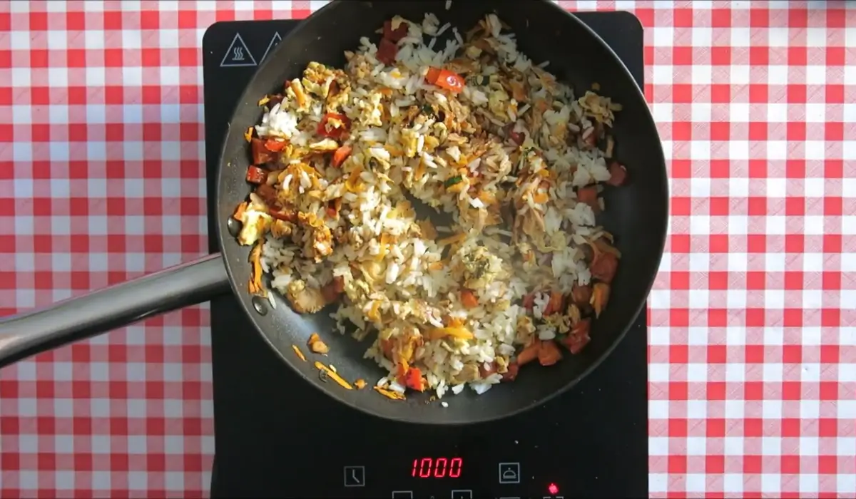 Rice being stirred with tuna, vegetables, and egg in a non-stick pan.