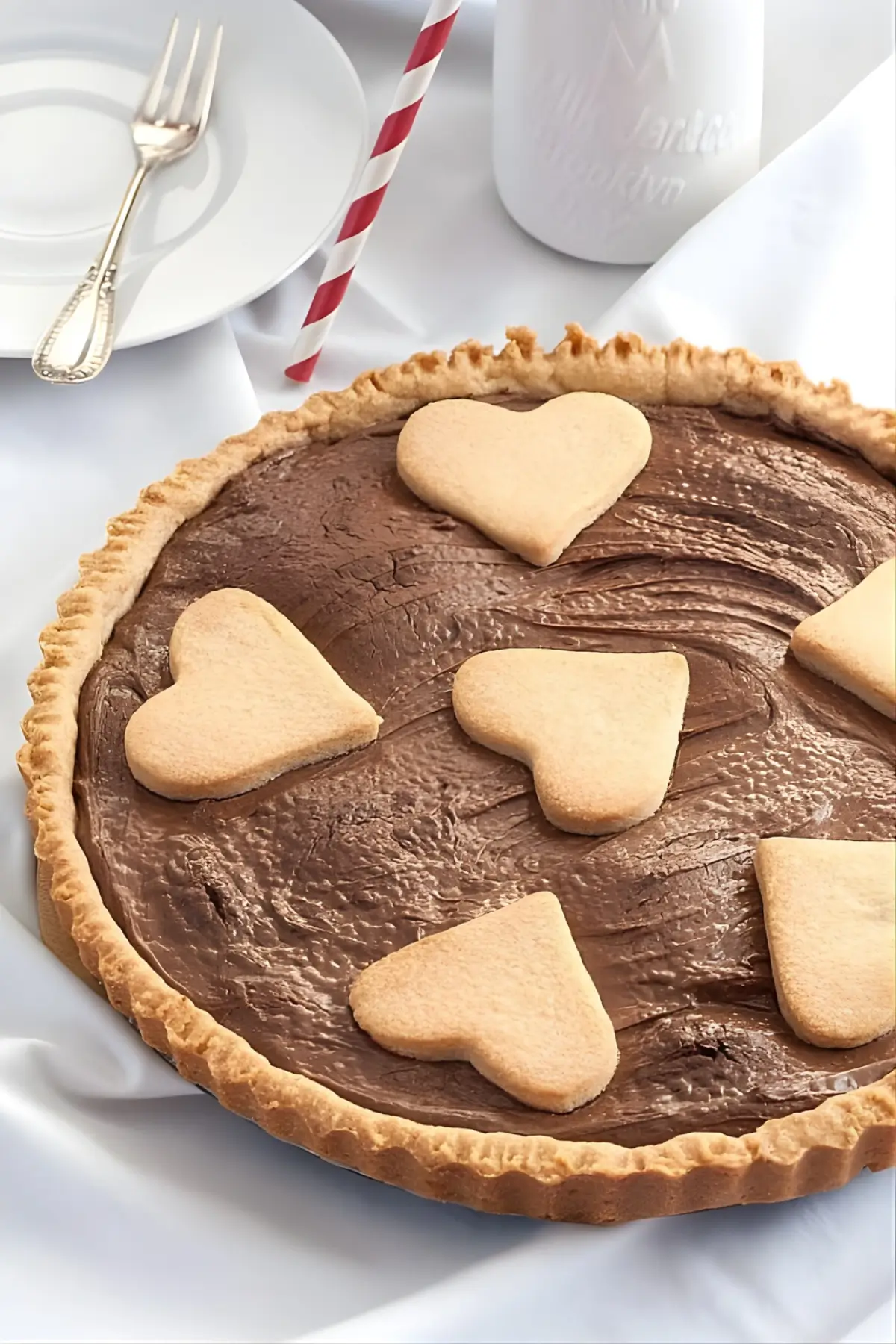 Nutella Crostata on a table with a plate, fork, and milk bottle.