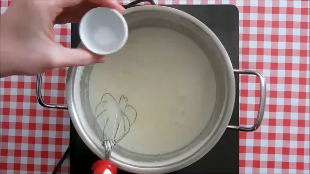 Adding soda bicarbonate to the simmering milk mixture.