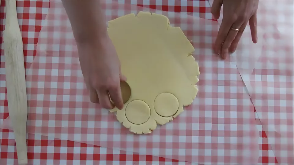 Rolling and cutting out round cookie shapes from the dough.