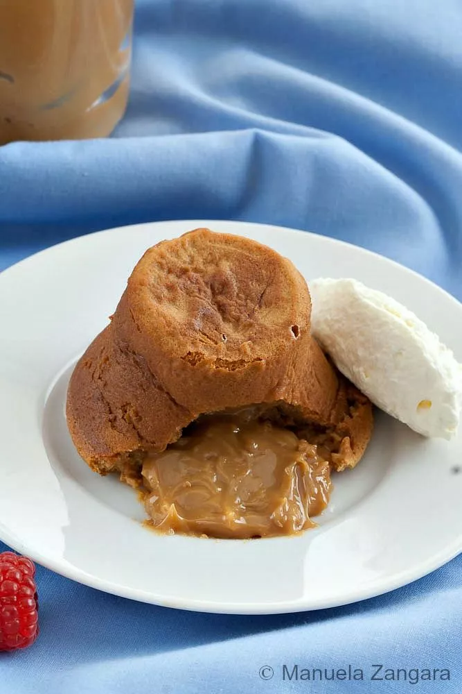 Molten Dulce de Leche Cake on a white plate with whipped cream on the side.