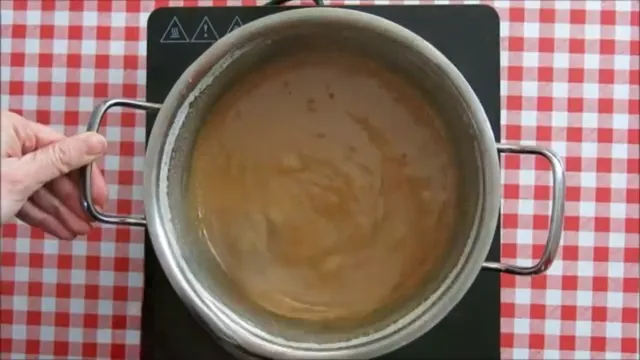 Thickened Dulce de Leche mixture turning golden brown as it cooks slowly.