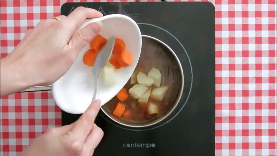 Carrots and potatoes being added to the pot.