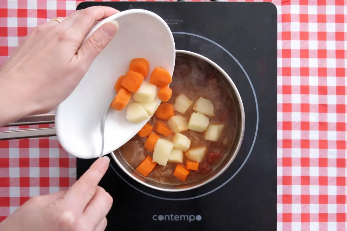 Carrots and potatoes being added to the simmering beef stew.