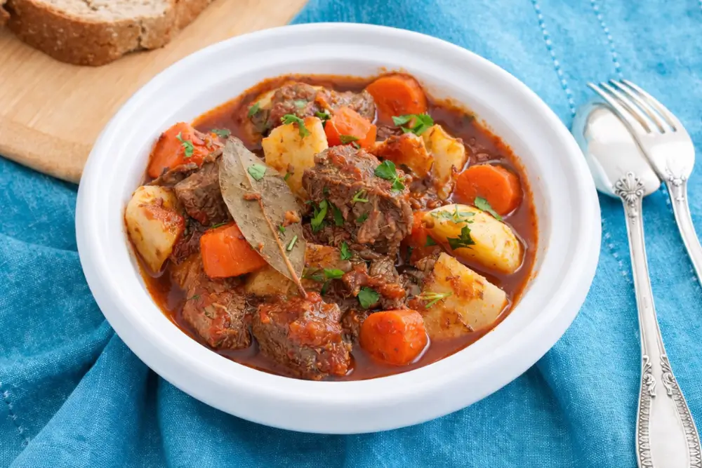 Close-up of beef stew with tender meat, carrots, and potatoes in sauce.